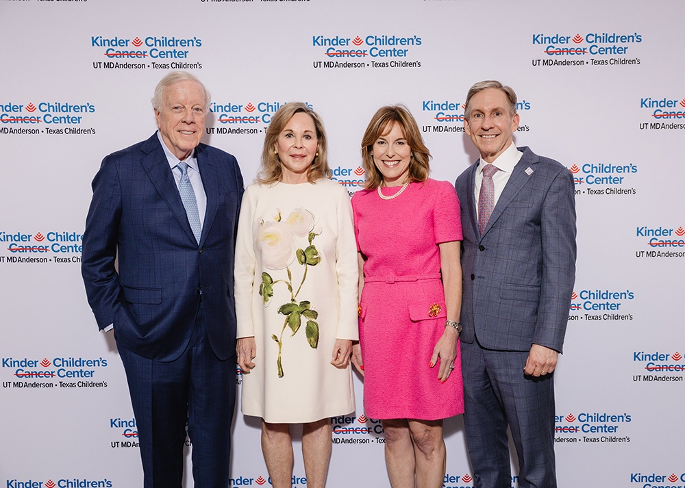 The Kinders, Sukin, and Pisters pose together in front of a backdrop with the new Kinder Children's Cancer Center logo.