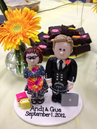 A cake topper with cartoon figures of Andi and Gus.