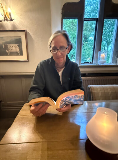 Rathmell seated at a table holding a book.