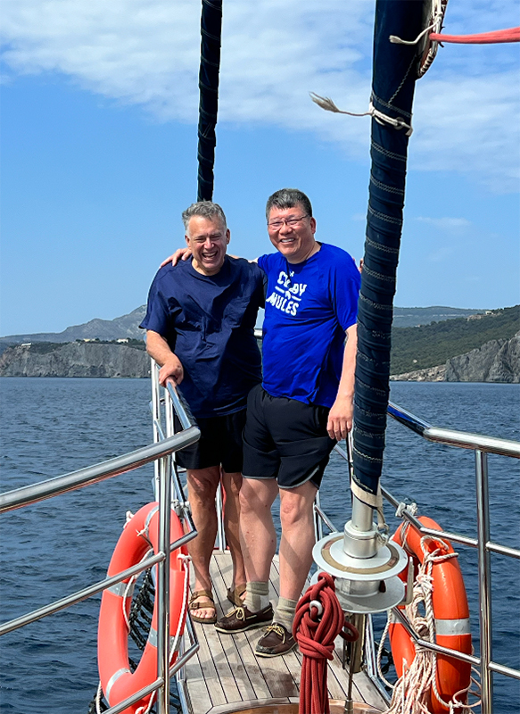 Herbst and Chu pose together on the bow of a boat with the ocean and Greek mountains behind them. 