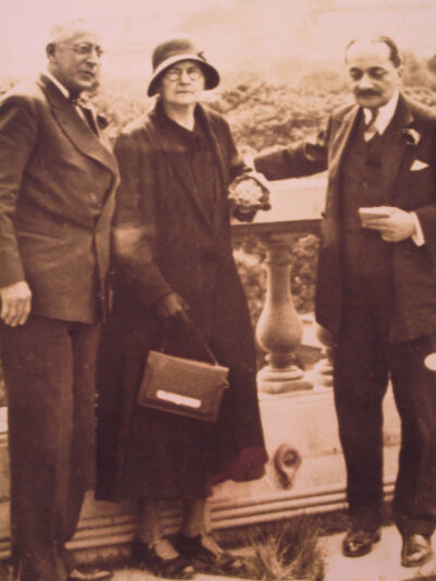 Marie Curie stands between two men holding an award.