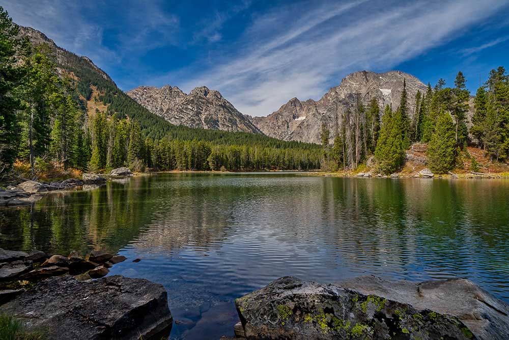 A lake reflecting trees and mountains in the background.