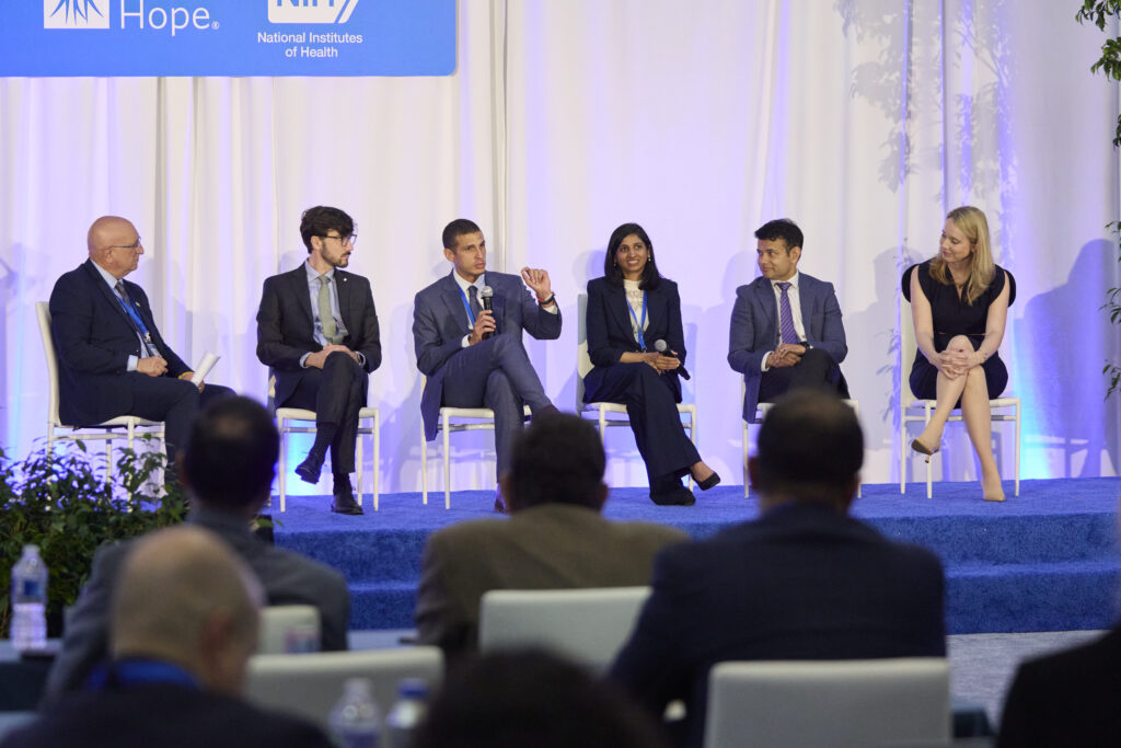 Five speakers sit on a stage giving a talk.
