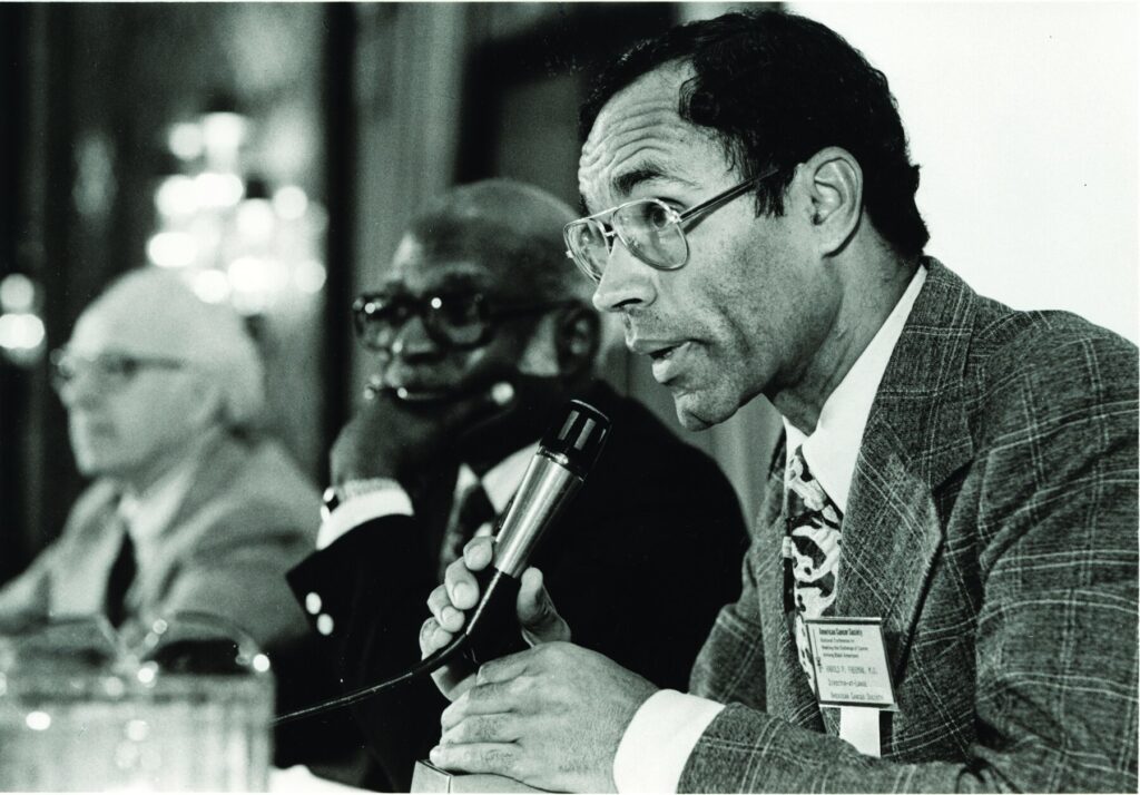 Freeman, wearing a name tag with his ACS title, leans over a microphone.