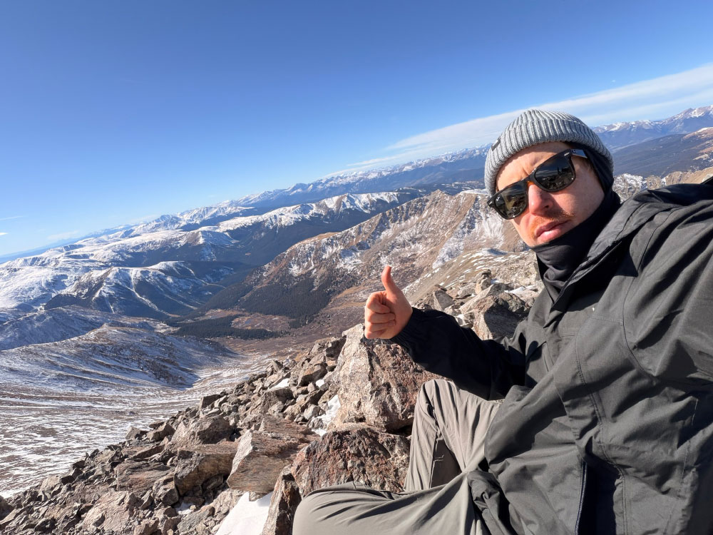 Herzer takes a selfie at the top of a mountain.